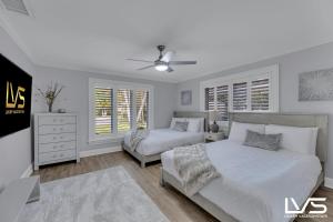 Un dormitorio blanco con dos camas y un ventilador de techo. en New Royal 80ft Waterfront Wlk2Beach HotPool Spa KitchenBBQ, en Fort Lauderdale