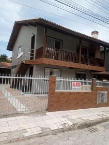 una casa con una cerca blanca delante de ella en Aluguel casa Bombinhas, en Bombinhas