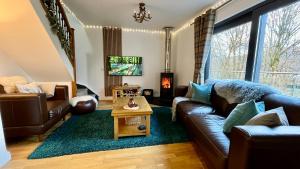 uma sala de estar com um sofá e uma mesa em Bluebell Cottage with Hot Tub em Ballachulish
