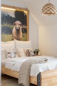a bedroom with a bed with a painting of a sheep at Pokoje Widokowe Sywarne in Kościelisko