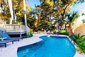 a swimming pool in a yard with chairs and trees at Eagle Watch in Hilton Head Island