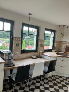 een keuken met een aanrecht met stoelen en ramen bij Landhaus Ana-Vital in Merzig