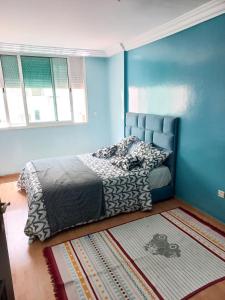 a bedroom with a bed with blue walls and a rug at Superbe Appartement à proximité de la corniche in Casablanca