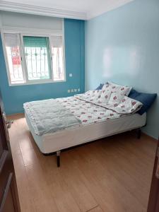 a bed in a bedroom with a blue wall at Superbe Appartement à proximité de la corniche in Casablanca