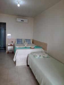 1 dormitorio con 2 camas y mesa. en Pousada Grão de Areia Beira Mar, en Mangue Seco