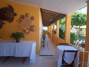 two tables on the side of a room with yellow walls at Pousada Grão de Areia Beira Mar in Mangue Sêco