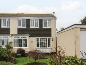 uma casa com janelas brancas e um quintal em Lamorna em Helston