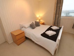um quarto com uma grande cama branca e uma janela em Lamorna em Helston