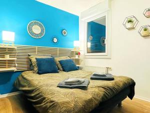 Schlafzimmer mit blauen Wänden und einem Bett mit blauen Kissen in der Unterkunft LOASIS - Appart T4 proche Gare et Centre Ville in Villefranche-sur-Saône
