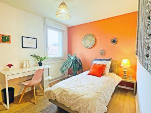 Schlafzimmer mit orangefarbener Wand, einem Bett und einem Schreibtisch in der Unterkunft LOASIS - Appart T4 proche Gare et Centre Ville in Villefranche-sur-Saône