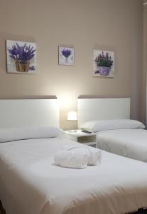 - une chambre avec 2 lits avec des draps blancs et des fleurs dans l'établissement Palacete de la Almudayna, à Madrid