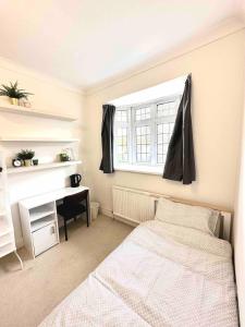 a bedroom with a bed and a desk and a window at Homestay - En-suites in New Malden