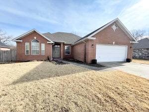 a brown brick house with a white garage at Bike in Bike out Coler The Trail House in Bentonville