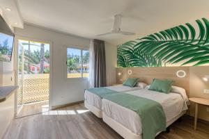 a bedroom with a bed with a large green leaf on the wall at Bungalows Cordial Green Golf in Maspalomas