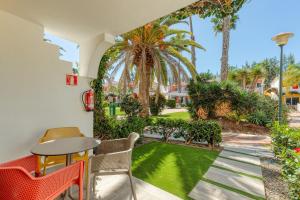 eine Terrasse mit einem Tisch und Stühlen sowie einem Garten in der Unterkunft Bungalows Cordial Green Golf in Maspalomas