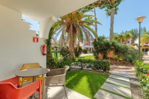 a patio with a table and chairs and a garden at Bungalows Cordial Green Golf in Maspalomas