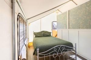 Cama en habitación pequeña con ventana en Silver Spur Homestead Luxury Glamping -The Tombstone, en Tombstone