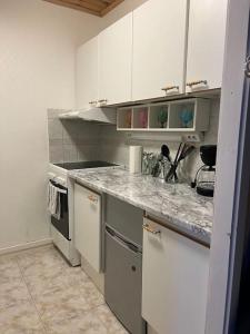 cocina con armarios blancos y encimera de mármol en Apartment Isokatu2, en Kokkola