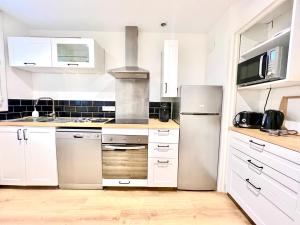 eine Küche mit weißen Schränken und einem Kühlschrank aus Edelstahl in der Unterkunft Stay house to Poitiers in Poitiers
