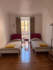 two beds in a room with a window at Apartamento Lisboa in Lisbon