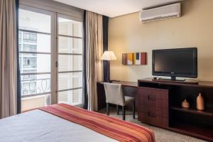 a hotel room with a bed and a desk with a television at DELPLAZA Marabá São Paulo in Sao Paulo