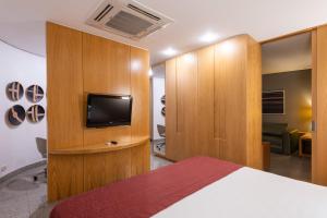 ein Schlafzimmer mit einem Bett und einem TV in einem Zimmer in der Unterkunft DELPLAZA Marabá São Paulo in São Paulo