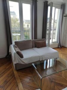 a couch in a living room with large windows at Bel appartement Montparnasse 70m2 in Paris