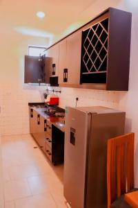 una cocina con nevera de acero inoxidable y armarios en The Vacation Homes Apartments en Kigali