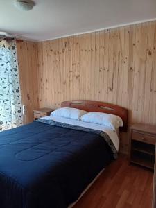 Schlafzimmer mit einem blauen Bett und Holzwänden in der Unterkunft Cabañas Lomas de Putagan in Linares