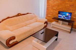 sala de estar con sofá y TV en The Vacation Homes Apartments en Kigali