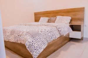 a bedroom with a bed with a wooden headboard at The Vacation Homes Apartments in Kigali