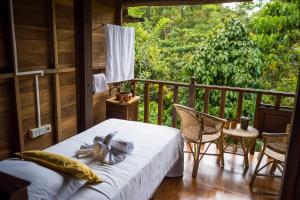 a bedroom with a bed and a balcony with a view at Wanakaset Forest Glamping in Kitulgala