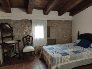 um quarto com uma cama, uma janela e uma cadeira em Maestrazgo Teruel Casa Marco em Luco de Bordón