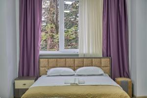 a bedroom with a bed with purple curtains and a window at Hotel Lile • სასტუმრო ლილე in Khulo