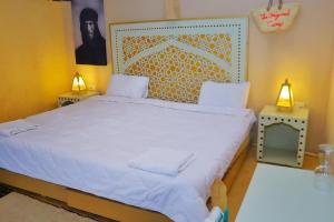 a bedroom with a large white bed with two lamps at The Original Camp in Aït Daoud
