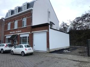 dos coches estacionados frente a un edificio con un garaje grande en Shelter-rooms, en Buysinghen