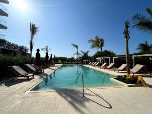 una piscina con tumbonas y palmeras en Apartamento en Cartagena - Morros Zoe, en Cartagena de Indias
