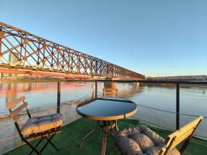 貝爾格勒的住宿－Savka Splav，一张桌子和椅子,享有桥梁的景色