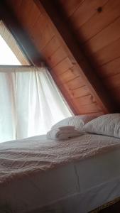 a bedroom with a white bed with a window at Cabañas Keikary in Valle de Bravo