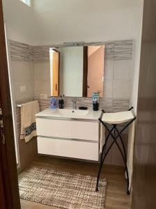 een badkamer met een wastafel, een spiegel en een kruk bij Charming Sardinian House in Cuglieri