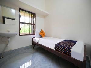 een slaapkamer met een bed, een wastafel en een raam bij Royal Adwita Resort in Cuttack