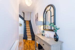 um corredor com uma mesa com um espelho e uma escada em Huge House in Leeds 6BR sleeps13 by PureStay Short Lets em Meanwood
