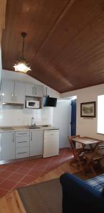 una cucina con armadi bianchi e soffitto in legno di Casa do Loureiro ad Arganil