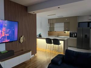 uma sala de estar com um sofá e uma cozinha com uma televisão em The Crown Pool Villa em Belgrado