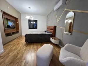a bedroom with a bed and two chairs and a mirror at The Crown Pool Villa in Belgrade