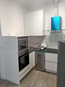 una cocina con armarios blancos y electrodomésticos de acero inoxidable en Apartamento Gran Vía Madrid W2, en Madrid
