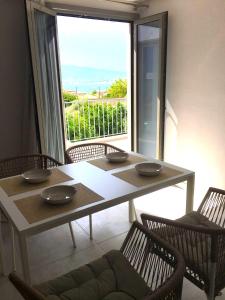 a dining room with a table and chairs and a large window at DION APARTMENTS in Paleros