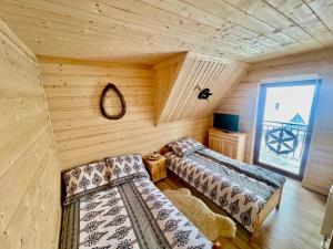 a log cabin with two beds and a window at Góralska Chatka in Kościelisko