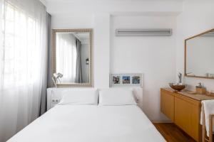 - une chambre blanche avec un grand lit et un miroir dans l'établissement La Mejor Zona de Barcelona, à Barcelone