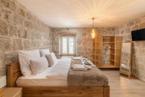 a bedroom with a large bed and a stone wall at Villa Rita Heritage Villas in Kaštela